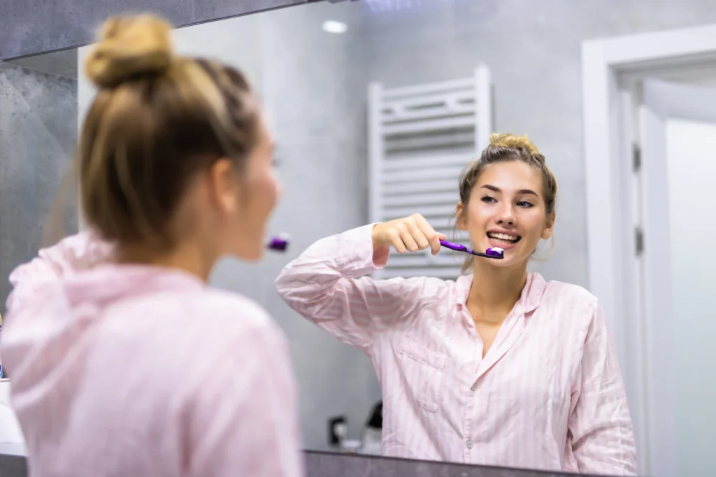 Une femme se brosse les dents, une technique pour prendre soin de ses gencives. Article blog du Centre Dentaire Cousineau à Brossard.
