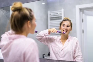 Une femme se brosse les dents, une technique pour prendre soin de ses gencives. Article blog du Centre Dentaire Cousineau à Brossard.