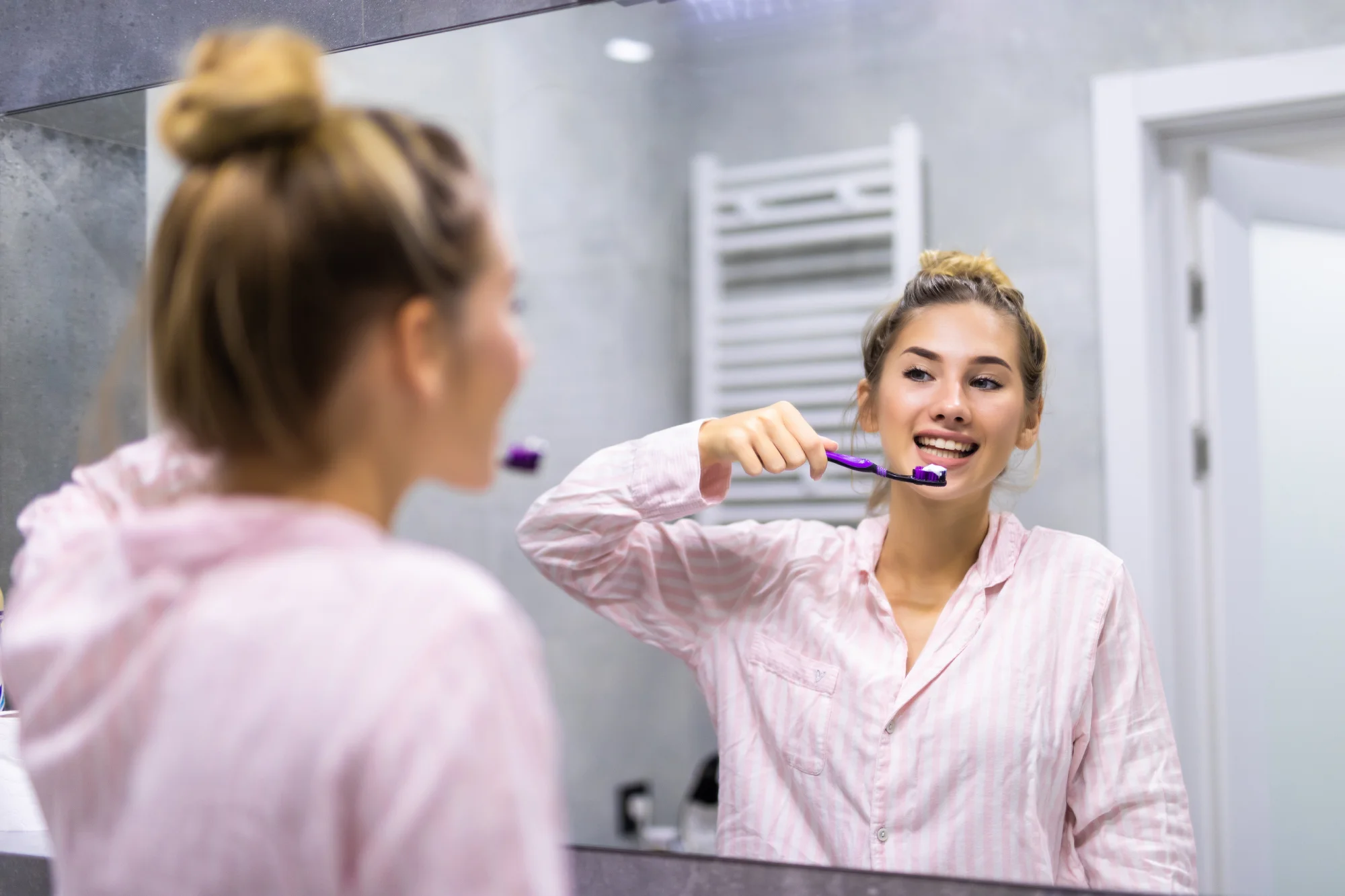 Une femme se brosse les dents, une technique pour prendre soin de ses gencives. Article blog du Centre Dentaire Cousineau à Brossard.