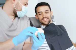 Le dentiste présente à un patient comment se passe la pose d'une couronne dentaire, Centre Dentaire Cousineau Brossard.